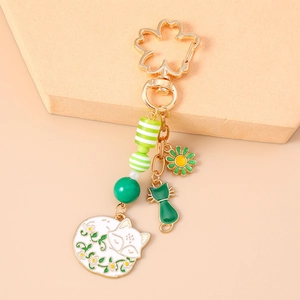 Detail von grünem Katzen- und Sakura-Blumenanhänger an goldenem Emaille-Schlüsselbund