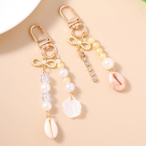 Golden nautical keychain with pearls, rhinestone bow, and sea shell charms in a summer style