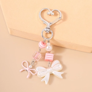 Detailed close-up of pink striped beads and pearlescent bow on a heart-shaped keychain