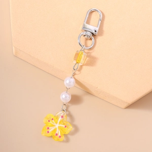Close-up of beaded flower keychain with yellow acrylic petal pendant and white pearls