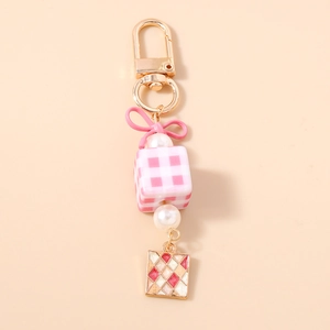 Close-up of pink ribbon keychain with checkered cube and faux pearls bag charm