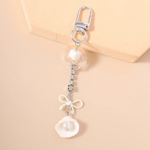 Détail de porte-clés chaîne strass avec nœud blanc et pendentif coquillage perlé élégant