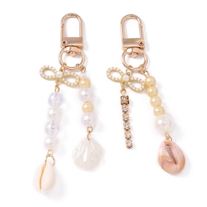 Elegant beaded shell keychains with pearls, rhinestones, and bows on a white background