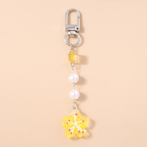 Detail of yellow flower keychain with resin cube bead and white pearls for bag charm decoration