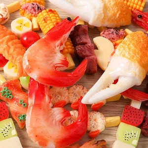 Close-up of assorted resin food miniatures including shrimp, crab claws, and fruit skewers