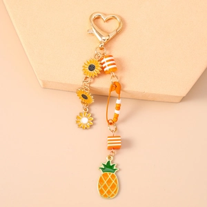 Detailansicht der Sonnenblumen- und Ananas-Anhänger mit goldenem Herzverschluss-Schlüsselanhänger