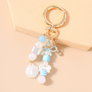 Vue détaillée d'un porte-clés perlé avec nœud bleu, coquillage et chaîne en strass