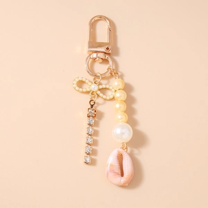 Detail of bohemian gold keychain with pearl bow, rhinestones, and natural seashell charm