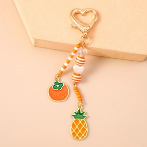 Detail der Perlenkette mit goldenem Herzverschluss und Fruchtanhängern wie Orange und Ananas