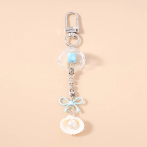 Détail d'un porte-clés avec nœud bleu clair, pendentif coquillage avec perle et strass