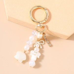 Détail du porte-clés perlé avec pendentif coquillage, nœud et chaîne en strass