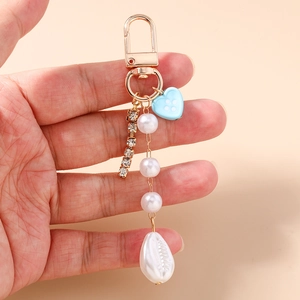 Dettaglio del portachiavi di perle con bottone a cuore blu e catena in metallo con strass
