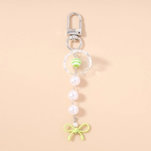 Détail d'un porte-clés perlé avec des perles blanches et un nœud vert clair