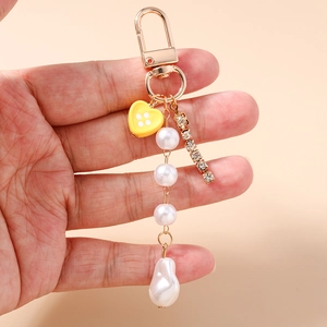 Dettaglio portachiavi con perle e cuore con chiusura dorata e nappina di strass lucidi