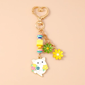 Detail eines goldenen Katzen-Schlüsselanhängers mit Emaille-Blumen und Regenbogen-Perlen