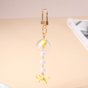 Détail d'un porte-clés en forme de méduse avec fermoir doré, perles et nœud jaune vif