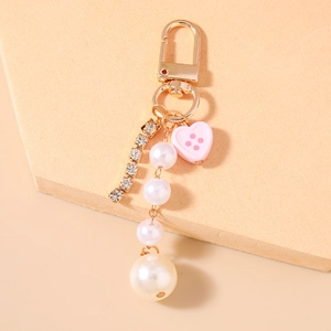 Dettaglio portachiavi con perle, ciondolo a cuore rosa e frangia di strass luccicanti