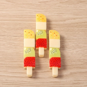 Detailed view of three resin fruit skewer charms on a wooden surface for DIY crafts