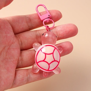 Close-up of pink turtle keychain made of translucent resin with metal lobster clasp