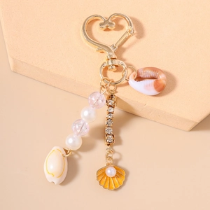 Détail de porte-clés marin avec perles, chaînes à strass, coquillages et fermoir cœur