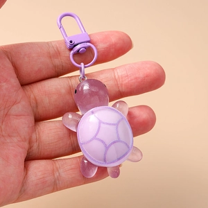 Detail of a purple resin turtle keychain with textured shell and matching metal clasp