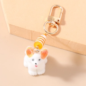 Gros plan d'un porte-clés chiot Corgi en peluche avec fermoir doré et perle rayée