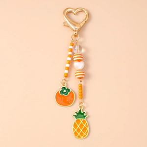 Detailansicht Frucht-Schlüsselanhänger mit goldenem Herzverschluss, Emaille-Ananas und Persimone
