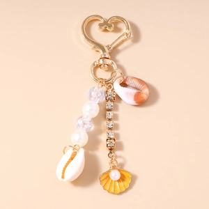 Détail d'un porte-clés de plage avec fermoir coeur doré, perles et breloques coquillages