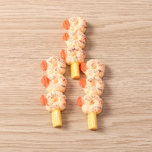 Macro shot of resin food charms featuring detailed fried shrimp skewers on wood