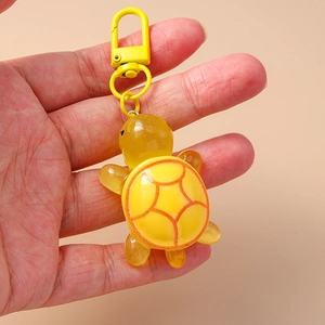 Close-up of yellow resin turtle keychain with metal lobster clasp held in hand