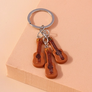 Music-themed guitar keychain featuring three brown resin pendants on a silver metal ring