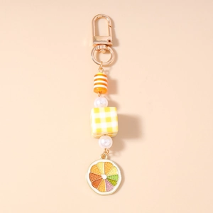 Detail of pearl beads keychain with checkered cube and colorful lemon slice pendant