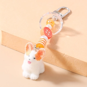 Vue macro d'un porte-clés chien floqué blanc avec perles colorées et boucle en métal
