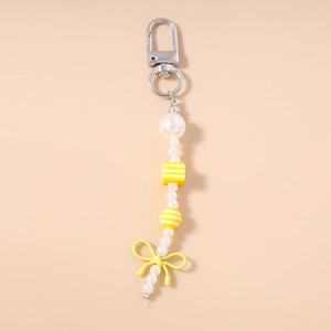 Close-up of pearl bead keychain with yellow bow pendant and striped round beads detail