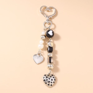 Détail de porte-clés cœur perlé avec plaque LOVE YOU et breloque étoile sur fond rose doux
