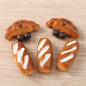 Detailed view of miniature resin croissant and baguette charms with metal loops