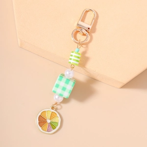 Detail of beaded keychain with checkered cube, pearl, and citrus slice charm