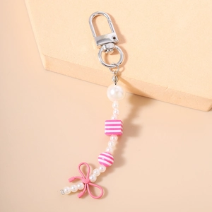 Detail of sweet pearl bead keychain with pink bow and silver lobster clasp on neutral base