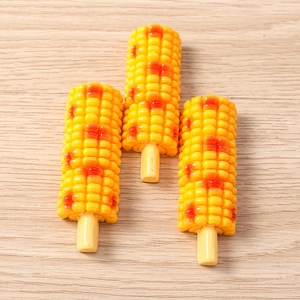 Detailed close-up of realistic resin grilled corn food models on a light wooden surface