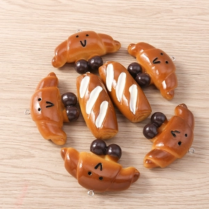 Close-up of resin food pendants featuring croissant and baguette shapes for DIY jewelry