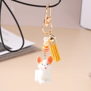 Détail d'un porte-clés chien corgi en peluche avec pompon et fermoir doré sur fond chaleureux