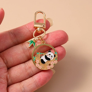 Détails d'un porte-clés panda doré avec du bambou vert et des breloques de fleurs roses