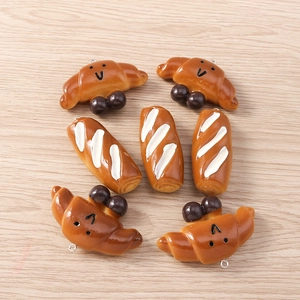 Macro shot of 4 realistic resin croissant charms with cute faces for DIY jewelry making