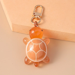 Close-up of translucent orange resin turtle keychain with premium golden lobster clasp
