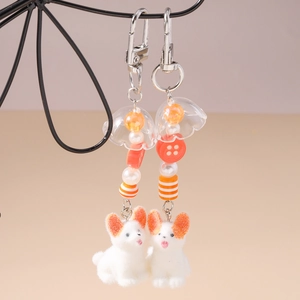 Vue détaillée de porte-clés chiens floqués avec pompons et perles colorées sur métal
