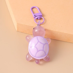 Close-up of a cute purple translucent turtle keychain with a metal carabiner on orange stand