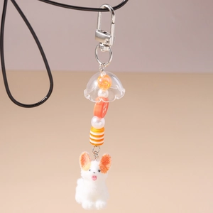 Détail d'un porte-clés chien en peluche orange avec boucle argentée et perles décor