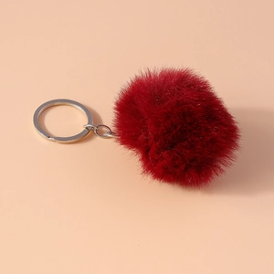 Macro view of burgundy faux fur pompom keychain with a silver metal ring accessory