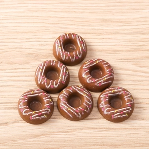 Vue macro de dessus de 6 breloques beignets en résine chocolat avec glaçage coloré