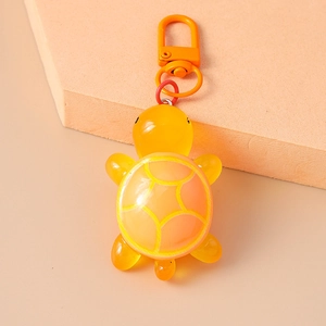 Close-up of cute yellow turtle keychain with smooth resin texture and orange hook